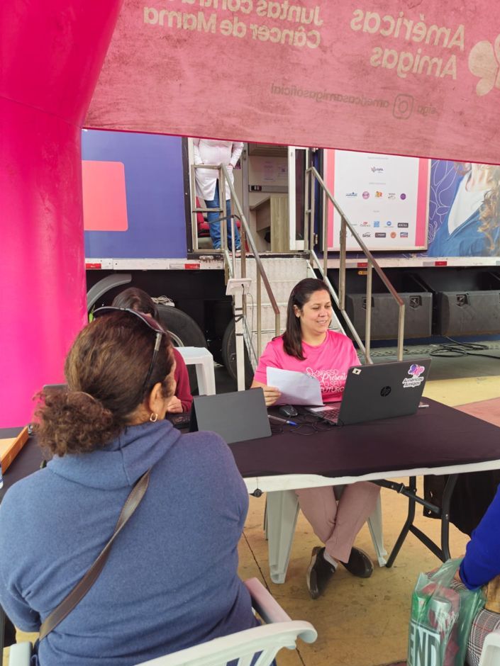 Atendente faz o cadastro de uma participante no notebook, sob a tenda da ação da Américas Amigas